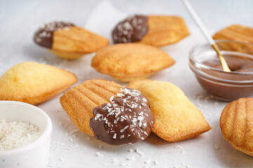 Delicious madeleines with chocolate and coconut flakes on white grunge background