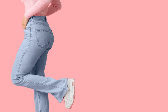 Young woman in stylish jeans on pink background