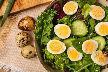 Bowl of tasty salad with boiled quail eggs and vegetables on table, closeup