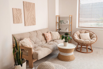 Interior of modern living room with comfortable sofa, coffee table, houseplants, armchair and pictures