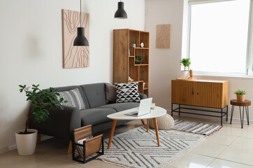 Interior of stylish living room with black sofa, coffee table, chest of drawers and shelving unit