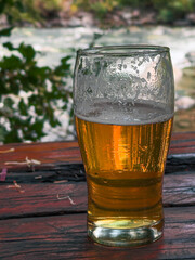 Glass of beer on a wooden table in front of the Rio Azul