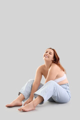 Naklejka premium Beautiful plus size woman sitting on light background