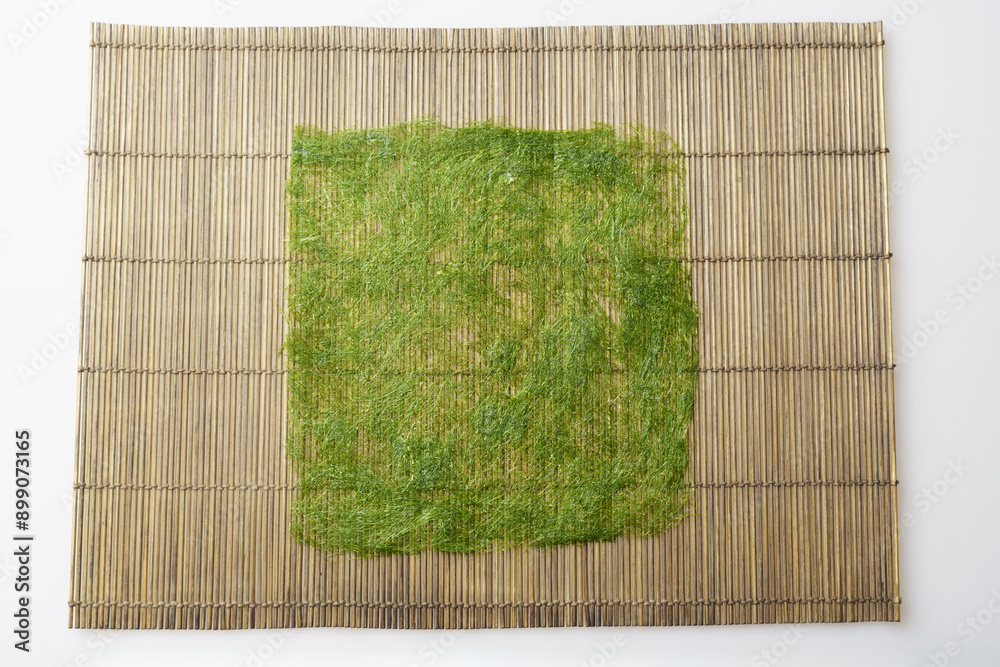 Sticker Close-up and top angle view of a dried green seaweed with rectangular cut on sushi roller mat, South Korea
