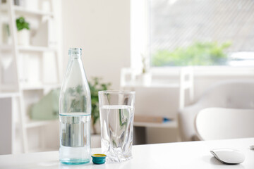 Bottle of water with glass on desk in light office, closeup