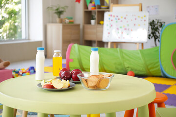 Apples with cookies, yoghurt and juice on table in kindergarten