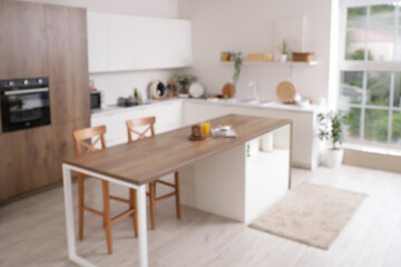 Blurred view of light kitchen with counters, table and plants