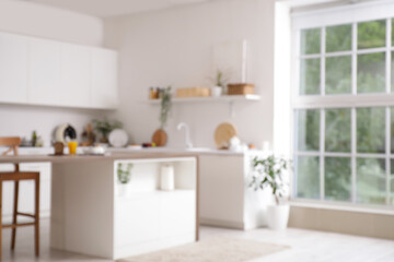 Blurred view of light kitchen with counters, table and plants