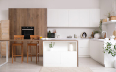 Blurred view of light kitchen with counters, table and plants