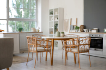 Blurred view of light kitchen with counters and dining table