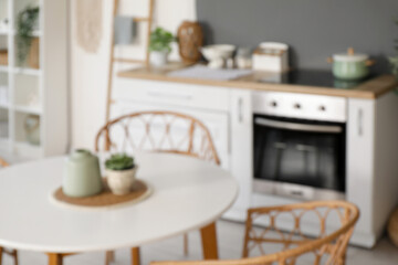 Blurred view of light kitchen with counters and dining table