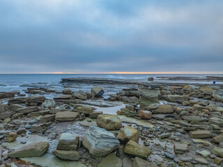 Sunrise seascape and rocky Inlet with thick fog cloud over the ocean