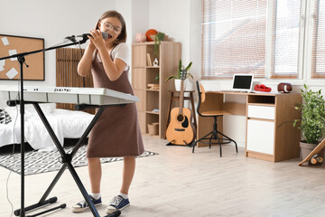 Cute little girl with microphone and modern synthesizer singing at home