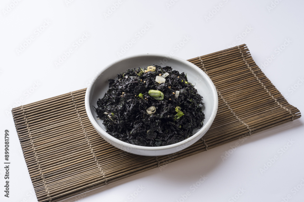 Poster Close-up of seasoned seaweed on white dish and sushi roller mat, South Korea
