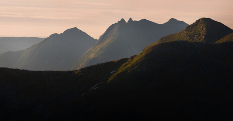 Panorama of setting sunlight from Tortenviktind ridge hike to the coastal mountains in the west....