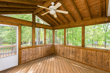 Cabin Wooden Sunroom With Large Windows And Ceiling Fan In Forested Area