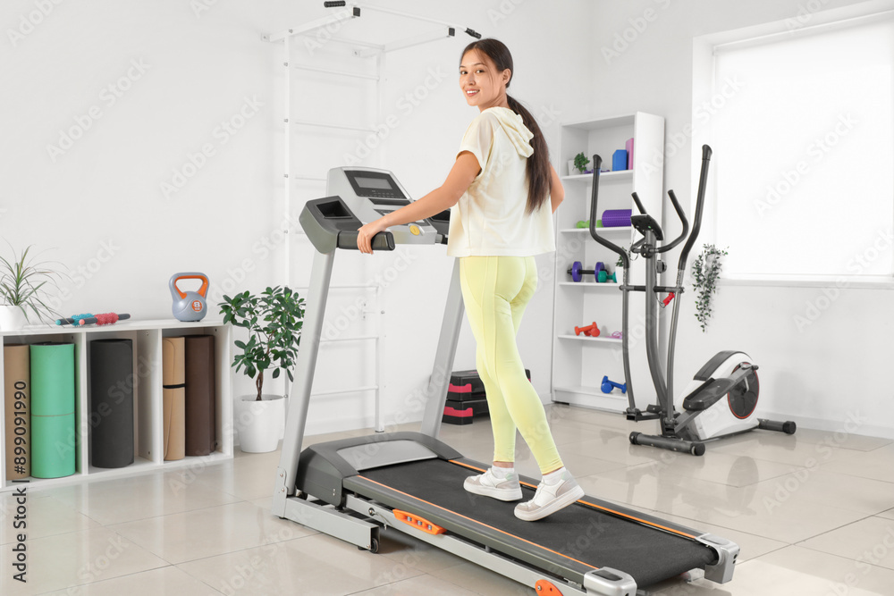 Poster Sporty Asian woman training on treadmill in gym