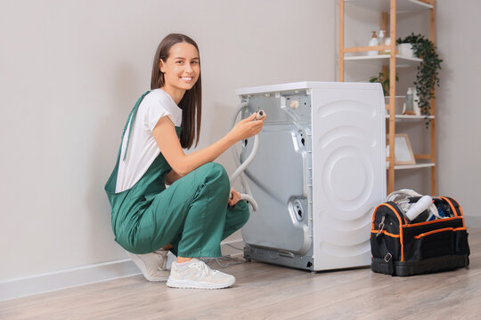 Female plumber fixing washing machine in bathroom