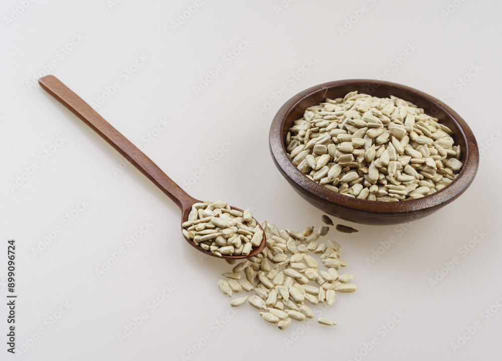 Sticker Close-up of sunflower seeds on a jar, wood spoon and white floor, South Korea
