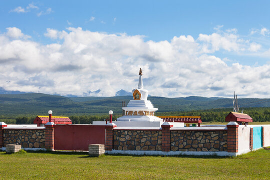 Siberia. Baikal region. Buryatia. Tunka valley. View of Buddhist Stupa against the background of the Eastern Sayan Mountains in  low cumulus clouds on sunny summer day