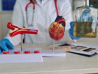 Doctor holds bottle of alcohol model of heart