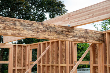 Closeup detail of new house construction, large glue laminate wood support beam crossing a Parallel...