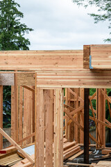 Closeup detail of new house construction, large glue laminate wood support beams and Parallel Strand Lumber support beams, building framing started with walls and windows
