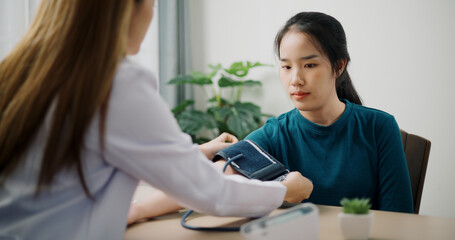 Selective focus ,Asian doctor checks blood pressure and gives advice to young female patient in...