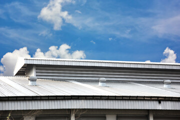 metal sheet roof tile of warehouse with ventilation fan on roof on blue sky white cloud