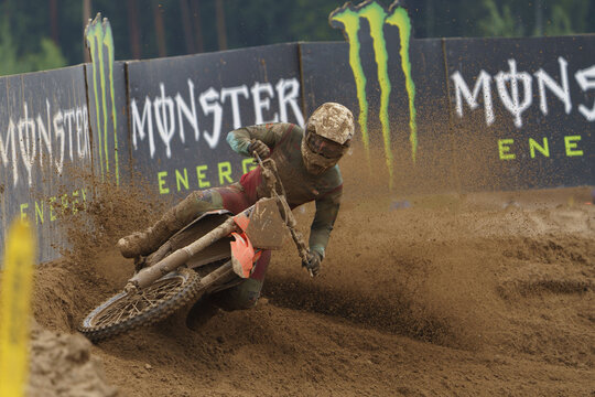 08-06-2024 Latvia, Kegums, MXGP  A man rides a dirt bike on a dirt track, background features a monster signt