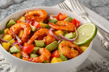 Prawn salad with avocado, mango, red onion, bell pepper and homemade dressing closeup on the bowl on the table. Horizontal