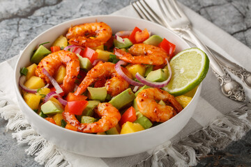 Delicious sweet and sour mango shrimp salad with red onion, bell pepper and avocado close-up in a bowl on the table. Horizontal