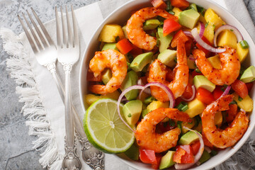 Bright rich salad mango shrimp avocado with red onion, bell pepper close-up in a bowl on the table. Horizontal top view from above