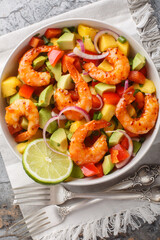 Shrimp Salad with Mango, Avocado, red onion, bell pepper with lime dressing closeup on the bowl on the table. Vertical top view from above