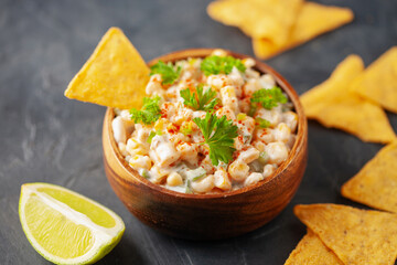Mexican street corn dip in bowl. Elote dip with nachos chips. Latin American cuisine