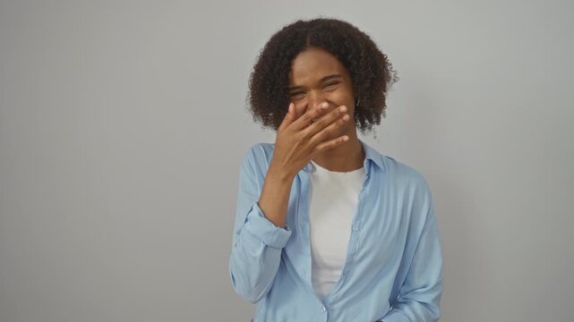 Laughing young african american woman wearing a shirt, standing and smiling hard out loud over a funny joke, isolated on a white background