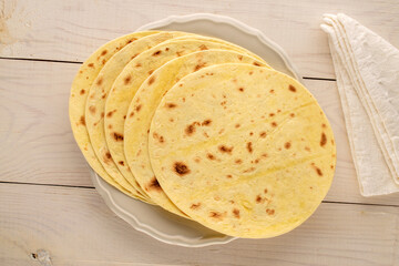 Several tasty tacos on a ceramic plate on a wooden table, macro, top view.