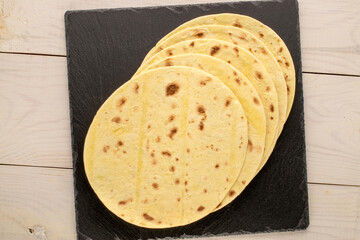 Several tasty tacos with slate stone on a wooden table, macro, top view.