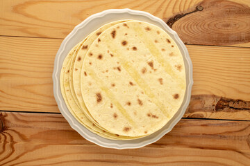 Several tasty tacos on a ceramic plate on a wooden table, macro, top view.