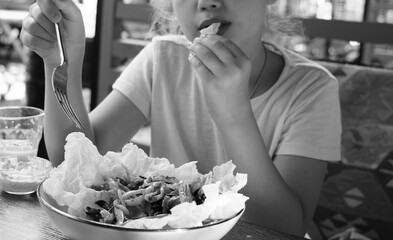 Girl eating salad with seafood, mix vegetables, chilli, peanut, sesame, crispy puffed rice. Black and white, cinematic, retro style