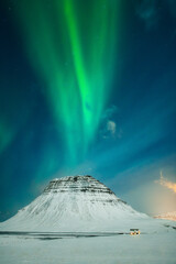 Incredible aurora borealis northern lights above the Kirkjufell mountain, bright green aurora