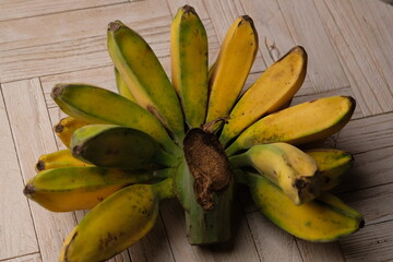 pisang Kepok Kuning (musa acuminata) or yellow local banana on the wooden table. bananas can be made into delicious and nutritious food preparations. Indonesian fruit. 