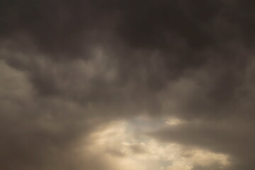 photo of storm clouds with a space through which the sky and light filter through,