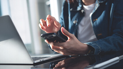 Business woman using mobile phone, working on laptop computer in office. Startup business woman, freelancer online working at home office. social media network, business technology