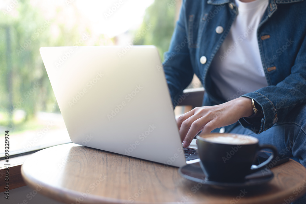 Wall mural Woman working on laptop computer at cafe, surfing the internet, business casual, freelance lifestyle