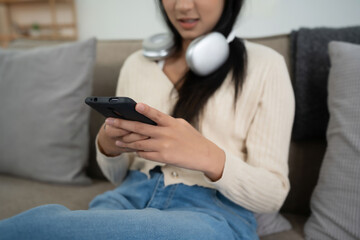 Closeup of young asian women surfing social media entertainment and typing message chatting on smartphone while sitting on the couch to spending time and relaxation with enjoying lifestyle at home