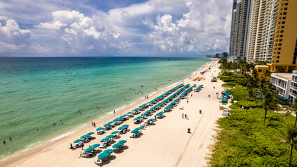Sunny Isles Beach, Florida - Rows of blue parasols dot the beach with luxury condos behind.