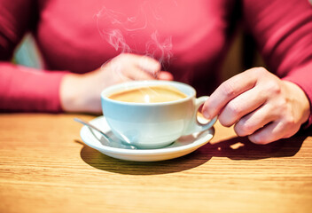 A girl drinks coffee at a table in a cafe
