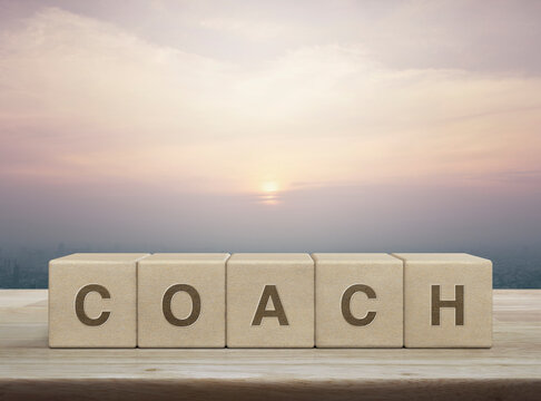 Coach letter on wood block cubes on wooden table over city tower and skyscraper at sunset, vintage style, Business, education and learning concept