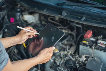 Close-up of Car mechanic noting repair parts during open car hood engine repair unrecognisable man...